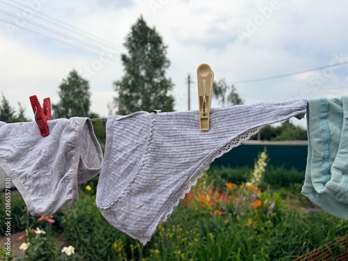 Children's and women's panties dry on a clothesline in the yard. Underwear dries outside in hot weather in the summer