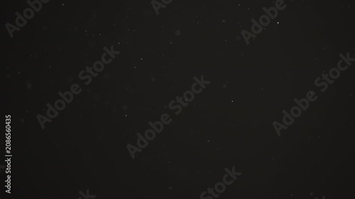 Floating dust particles over dark background with shallow focus