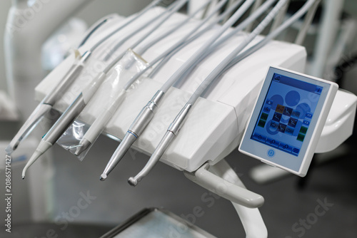 Quadro su tela Close-up of modern dental instruments and handpieces mounted on a dental treatment unit with a touchscreen control panel in a clean clinical environment