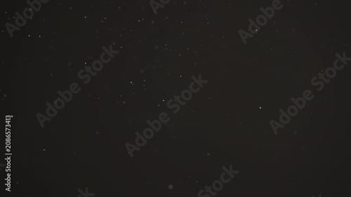 Floating dust particles over dark background with shallow focus