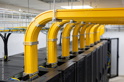 Organized yellow cable trays above server racks in a data center