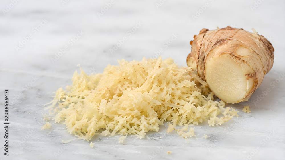 Fototapeta premium Freshly grated ginger and whole root on white marble