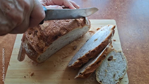 Old Man Slicing Homemade Rustic Walnut and Raisin Bread