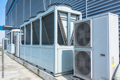 Obraz na płótnie Industrial air conditioning units lined up outside a modern building facade