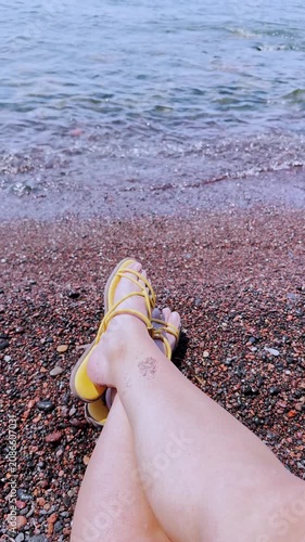 Woman's legs relaxing on volcanic red beach in santorini