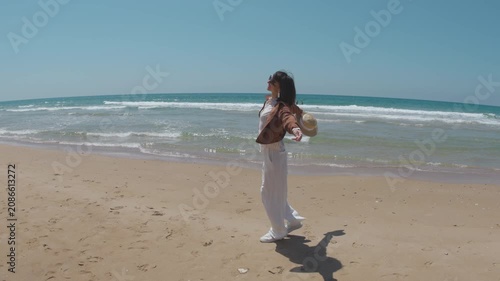 Summer mood. A smiling woman walks along a sandy beach, enjoying the moment. a young woman strolling on the beach.