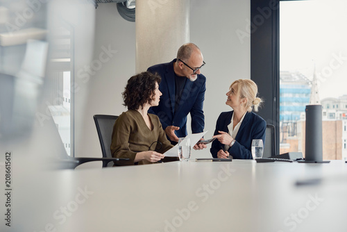 Business colleagues discuss work in a modern London office boardroom