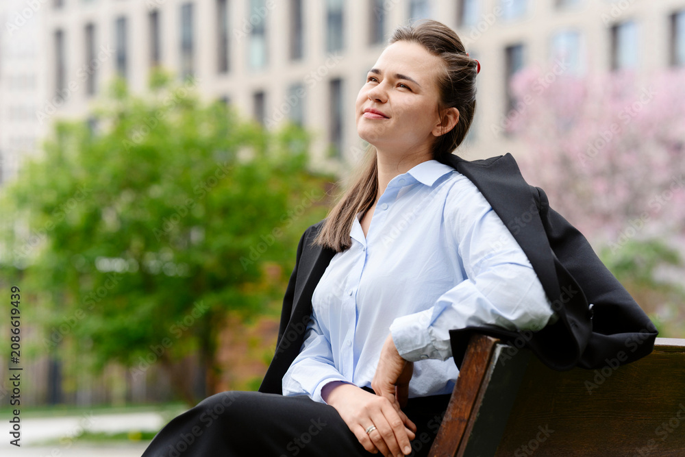 © BusinessClass by W61 - Confident businesswoman takes a break on an outdoor bench © BusinessClass by W61 - Confident businesswoman takes a break on an outdoor bench
