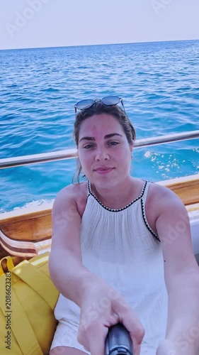 Female vlogger taking a selfie video on a boat in santorini, greece