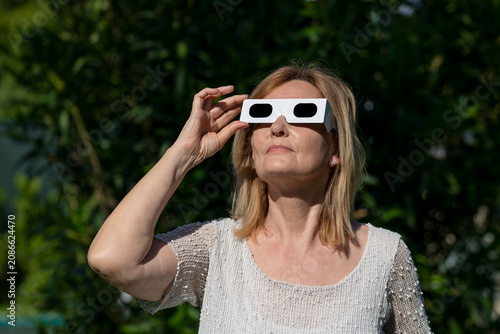 A woman is wearing a pair of special glasses to observe the sun without damaging her eyesight, waiting for the solar eclipse of summer 2026 on August 12
