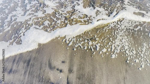 Aerial Perspective of Foamy Ocean Waves Rushing onto a Sandy Shoreline During Receding Tide