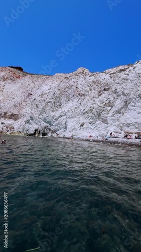 People swimming near the volcanic cliffs of santorini island, greece