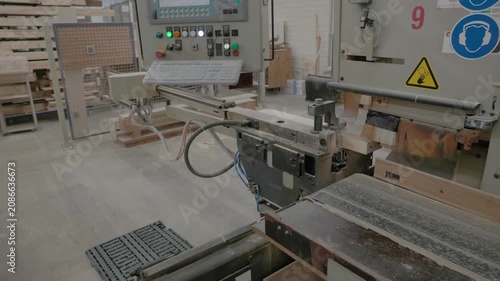 Worker operating industrial woodworking machinery to process a wooden frame component in a factory workshop