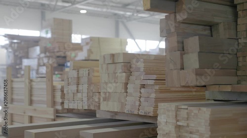 Stacked wooden profiles with marked measurements stored on factory shelving for window frame production
