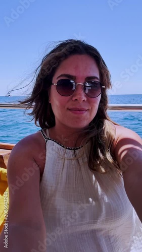Woman sailing on boat taking a selfie video in santorini