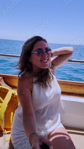 Young woman vlogging on a boat in santorini, greece