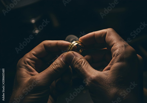 Artisan's Hands Skillfully Crafting a Gold Ring in a Dimly Lit Workshop With Engaging Light Reflections and Focused Attention to Detail