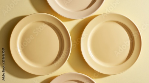 Soft yellow plates arranged in a top view layout on a light yellow background, showcasing a minimalist design ideal for table settings or culinary presentations
