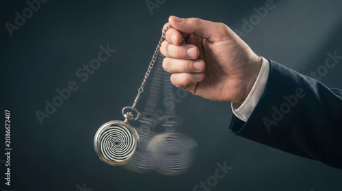 Hypnotic pocket watch swinging on chain held by hand in suit, creating blurred motion effect with spiral pattern
