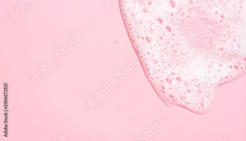 Soap foam texture on pink background, shampoo bubbles, hygiene and bath care concept. Close-up.