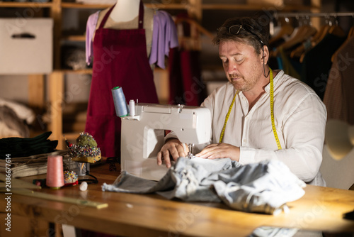 Photos Middle-aged male dressmaker working with sewing-machine