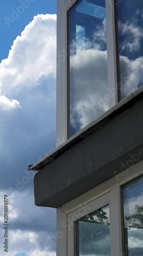 Vertical shot of white clouds reflecting in a modern building window