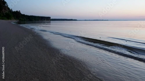 Sunset at the beach with gentle waves touching the shore and sand