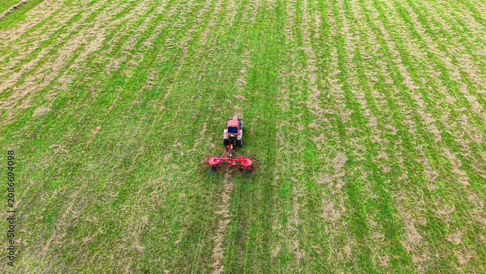 Fototapeta premium Tractor cultivating green field using a rotary tiller for soil preparation and farming tasks
