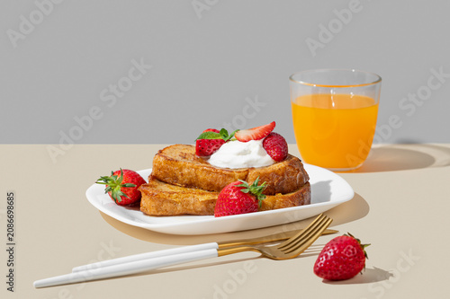 Brioche toasts with strawberries and whipped cream, drizzled with honey on a plate