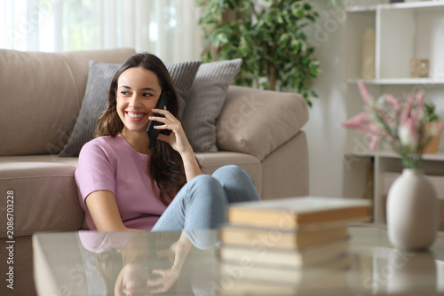 Happy woman talking on phone looking at side at home