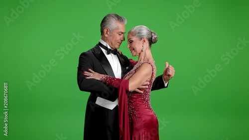 Elegant mature couple dancing ballroom tango, showcasing love and grace on green screen background. Sophisticated elderly partners in formal wear performing classic dance moves for professional media.