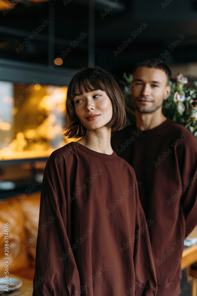 Fototapeta premium Stylish couple portrait in matching brown outfits for fashion banner and lifestyle background with warm cafe setting