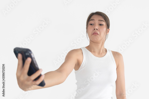 Young Thai Woman Holding Smartphone with Disgusted Unimpressed Expression on White Background