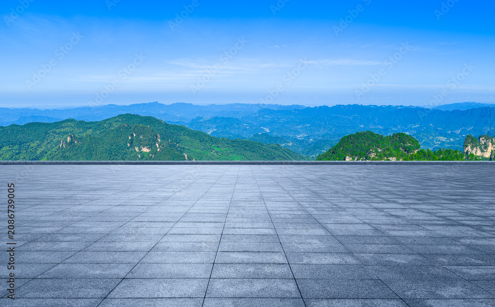 Naklejka premium Empty plaza overlooking green mountain range under blue sky in China