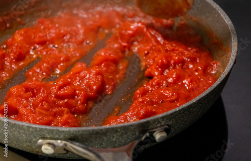 Close-up of fresh, flavorful tomato sauce simmering and bubbling gently in a rustic frying pan