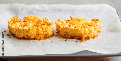 Close-up of golden-brown roasted cauliflower steaks in a baking tray