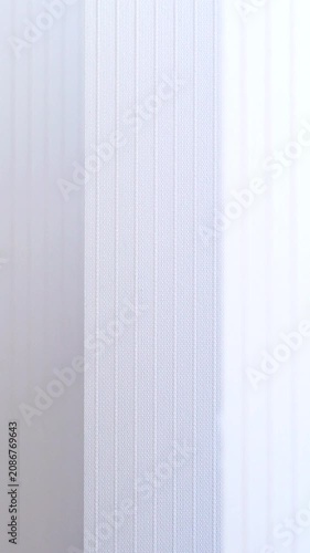 Abstract view of moving white window blinds in soft breeze.