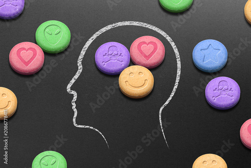 Human head silhouette filled with MDMA or Ecstasy pills on black background