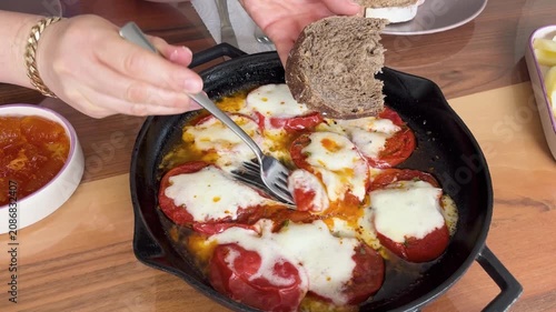 Delicious tomato slices with melted cheddar cheese in a cast-iron skillet. A warm, appetizing, and freshly prepared Mediterranean recipe for breakfast.