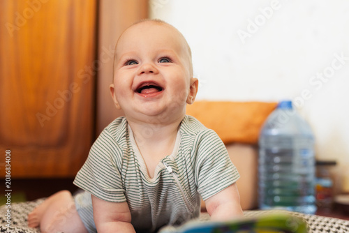 фотографія Cute baby giggling while sitting on the floor, enjoying playtime