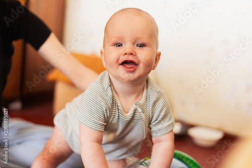 Fotografie Happy baby crawling and smiling with tongue out, looking at the camera