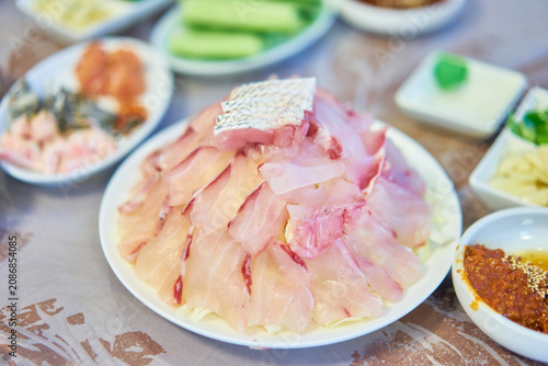 Premium raw croaker sashimi with traditional dipping sauces served for the summer boknal season. Captures authentic regional coastal gastronomy and is perfect for culinary travel or restaurant media.