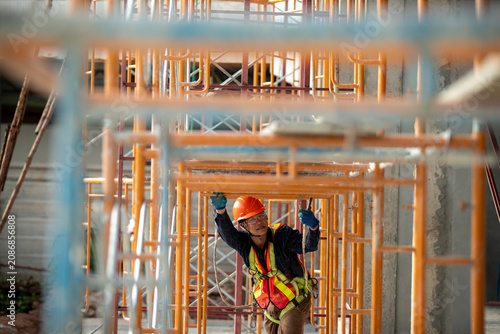 Tableau sur toile Engineer working on construction site wearing safety gear and climbing scaffoldi