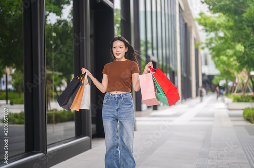 Obraz na płótnie Smiling asian woman walking and holding shopping bags, Fashion shopping, retail