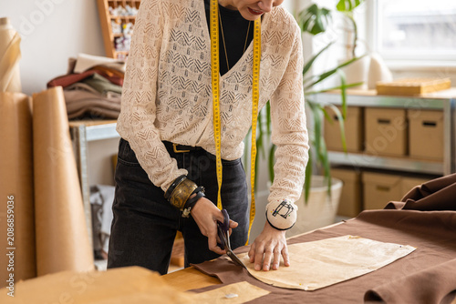 Canvastavla Tailor in white lace cardigan cutting fabric on table