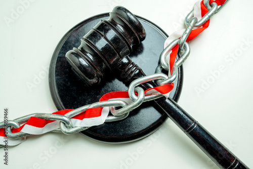 Obraz na płótnie A dark wooden judge's gavel and sound block bound tightly with a metal chain and