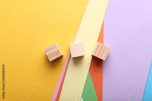 Obraz na płótnie Three wooden cubes on a colored paper background