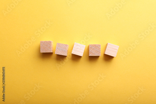 Five blank wooden cubes on yellow paper background