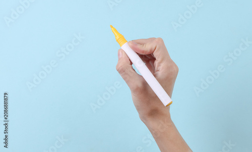 Photography Woman's hand draws with yellow felt-tip pen on a blue background