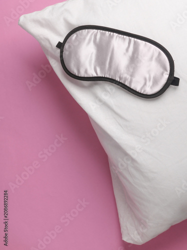 Sleeping mask with pillow on a pink background. Healthy sleep concept